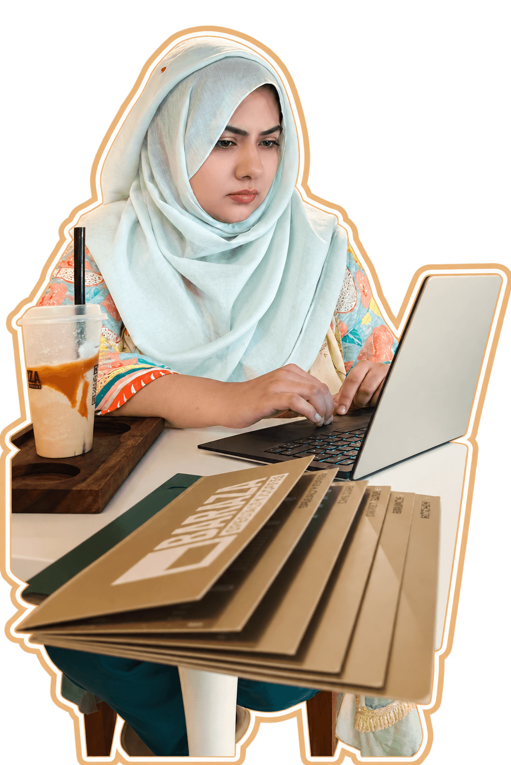 Sundas Waqar working on a laptop, with an iced coffee and a stack of printed menus